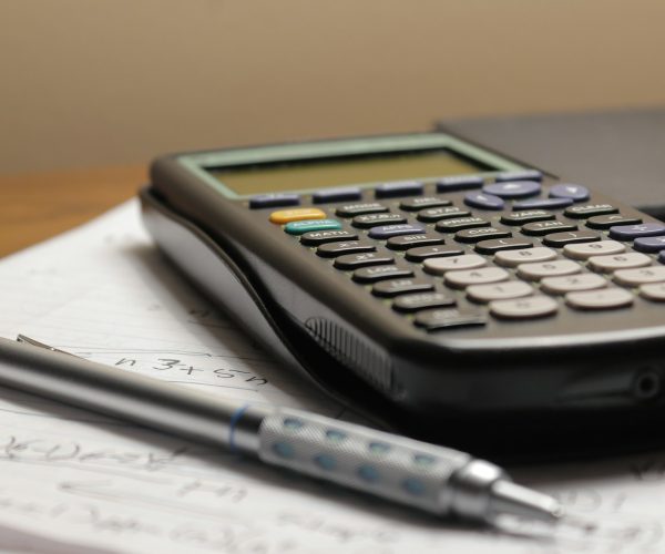 a calculator and a pen sitting on top of a piece of paper